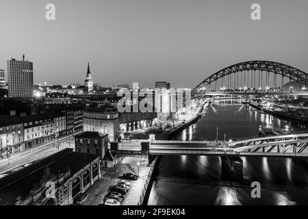 Newcastle upon Tyne Großbritannien: 30. März 2021: Newcastle Gateshead Quayside bei Nacht, mit der Tyne Bridge und der Skyline der Stadt, Langzeitbelichtung in Schwarzweiß Stockfoto