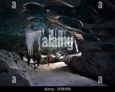 Eine Gruppe von Touristen, die die Sapphire Ice Cave, die sich im Gletscher Breiðamerkurjökull, Vatnajökull, Island, befindet, auf einer Tour mit einem moulin-Loch erkunden. Stockfoto