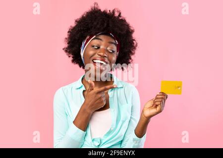 Fröhliche Schwarze Frau, Die Im Studio Mit Dem Finger Auf Die Kreditkarte Zeigt Stockfoto