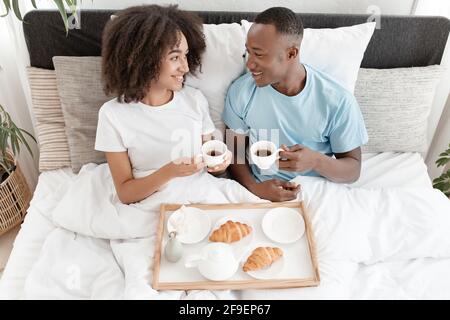 Schöner Morgen und romantisches Paar in der Liebe mit Frühstück im Bett, Ruhe und entspannen Sie sich zu Hause Stockfoto