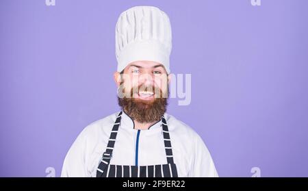 Sonderangebot vom Küchenchef. Selbstbewusste, bärtige, fröhliche Chefuniform in Weiß. Versuchen Sie etwas Besonderes. Meine geheimen Tipps kulinarisch. Kochen einfach und angenehm Stockfoto