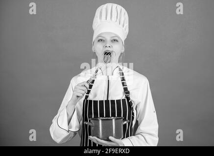 Frau professionelle Koch halten Schneebesen und Topf. Peitschend wie ein Profi. Mädchen in der Schürze peitschende Eier oder Creme. Beginnen Sie langsam mit Schlagsahne oder Schlagsahne Stockfoto