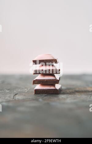 Selektive Konzentration auf vier Schokoladenscheiben auf dunklem Hintergrund. Stockfoto