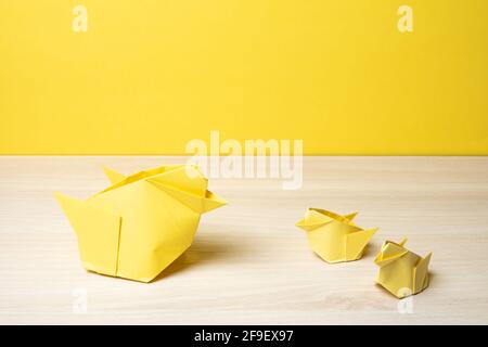 Eine gelbe Origami-Henne und Küken auf einem Holztisch Mit Copyspace Stockfoto