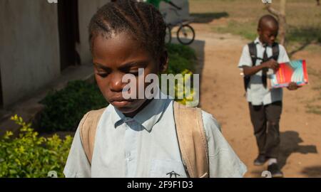 Dodoma, Tansania. 08-18-2019. Ein junges schwarzes Mädchen mit einem ernsten Gesicht geht von der Schule in Richtung ihrer Heimat in Tansania. Stockfoto
