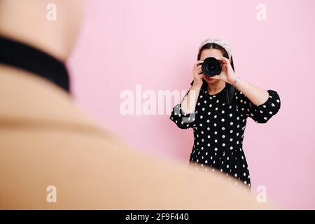 Kamerafrau in bescheidenen Kleidern, die Fotos von einem Mann machen Vordergrund Stockfoto