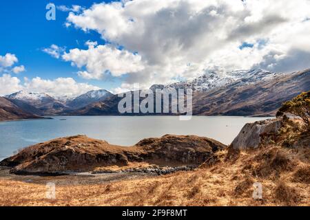 GLENELG HIGHLANDS SCHOTTLAND DIE STRASSE NACH ARNISDALE UND BLICK AUF LOCH HOURN UND SCHNEEBEDECKTE BERGE IM FRÜHJAHR Stockfoto