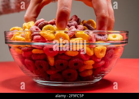 Eine Nahaufnahme der Hand eines Mannes, der Frühstückszerealien packte Ringe in einer Schüssel Stockfoto