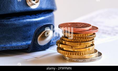 Eine Brieftasche mit mehreren Münzen auf dem Hintergrund einer Quittung. Das Konzept der Zahlung von Rechnungen Stockfoto