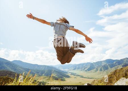 Guy springt auf einen Berg im Hintergrund Von Bergen in Karate-Pose Stockfoto