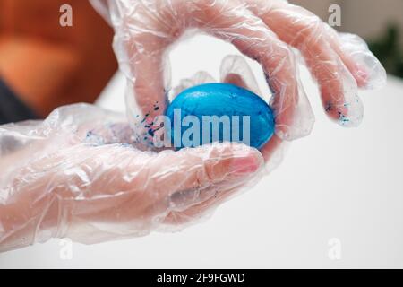 Eine Frau malt ein Hühnereier in blauer Farbe für Osterferien Stockfoto