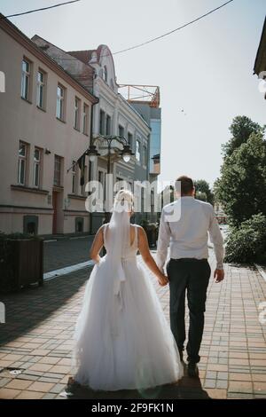 Eine vertikale Aufnahme eines Bräutigams und einer Braut, die weiter gehen Die Straße Stockfoto