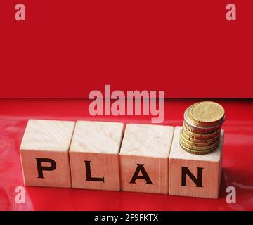 Wortplan mit Buchstaben auf Holzblöcken und Münzstapel. Geschäftsplan. Stockfoto