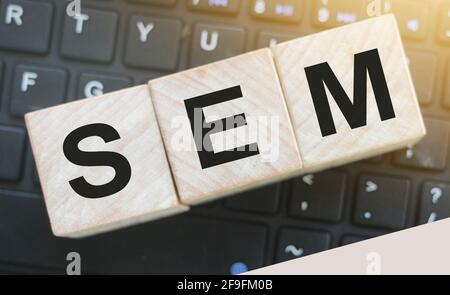 SEM Search Engine Marketing auf einem hölzernen Würfel geschrieben, der auf Computertastatur gesetzt wird. Optimierung Online Business Technologie Konzept Stockfoto