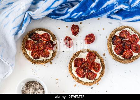 Runde Scheiben Vollkornbrot mit gegrillten Tomaten auf Frischkäse. Draufsicht. Stockfoto