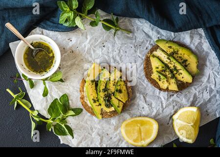 Runde Scheiben Vollkornbrot mit Avocado und Pesto, Kräutern und Zitrone. Draufsicht. Stockfoto