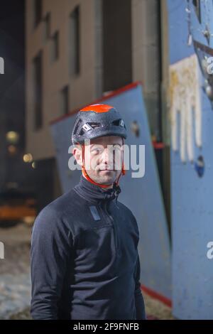 Ein vertikales Porträt eines kaukasischen männlichen Athleten, der im Bild steht Vor einer Kletterwand Stockfoto