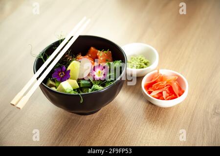 In einer Schüssel neben Wasabi und Ingwer Salat mit Lachs anrichten. Zutaten frischer Lachs, Avocado, Gurke, Reis, Tamarindensauce, Mangosauce, Nori Limette Stockfoto