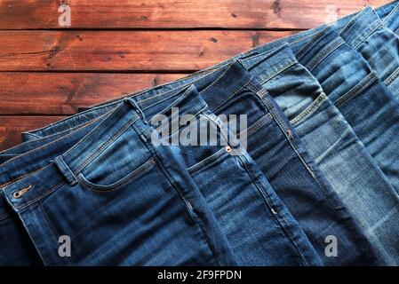 Stapel von blauen Jeans isoliert auf Holzhintergrund. Modebekleidung Konzept. Direkt darüber. Stockfoto