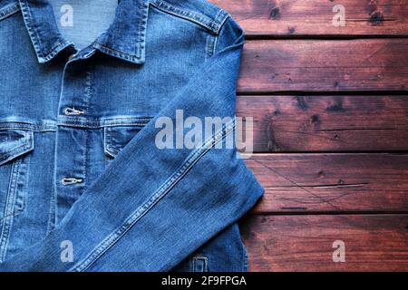 Blaue Jeansjacke auf Holzhintergrund. Direkt darüber. Modebekleidung Konzept. Stockfoto