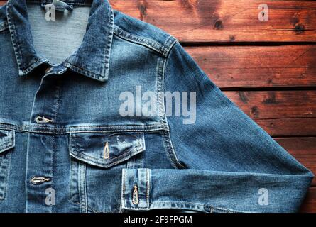 Blaue Jeansjacke auf Holzhintergrund. Direkt darüber. Modebekleidung Konzept. Stockfoto