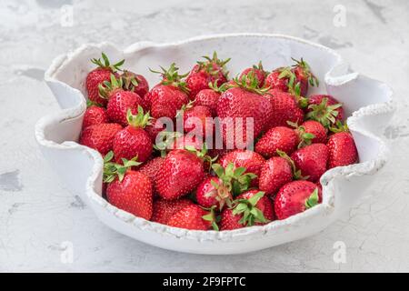 Handgemachte weiße Töpferschale mit frischen Erdbeeren auf weißem Hintergrund Stockfoto
