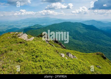 Blick vom Pikui Berg. Riesige Steine auf den grasbewachsenen Hängen. Sommerlandschaft der karpaten Berge. borzhava Bergrücken in der Entfernung unter einem Himmel wi Stockfoto