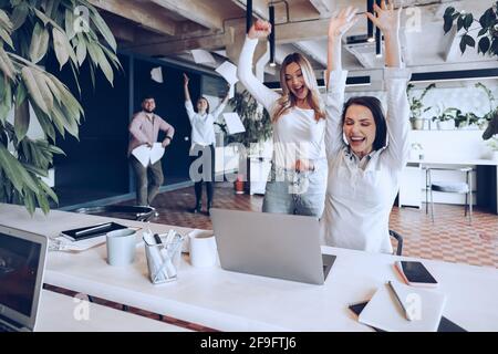 Zwei junge glückliche Geschäftsfrauen feiern den Projekterfolg im Büro Stockfoto