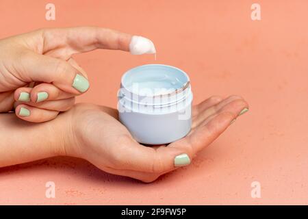 Nahaufnahme der jungen Dame mit offenem Glas Creme auf rosa Hintergrund, leeren Raum Stockfoto