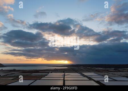 El Golfo, Lanzarote, Kanarische Inseln, Spanien. Blick über die Salinas de Janubio auf den Atlantischen Ozean, Sonnenuntergang. Stockfoto