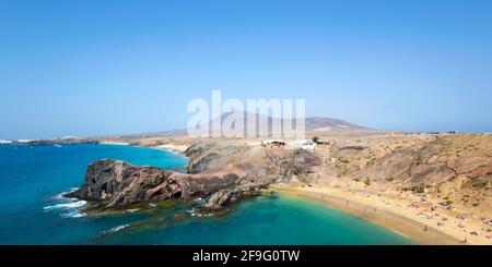 Playa Blanca, Lanzarote, Kanarische Inseln, Spanien. Panoramablick entlang der Küste von der Klippe über Playa del Papagayo, Atalaya de Femés im Hintergrund. Stockfoto