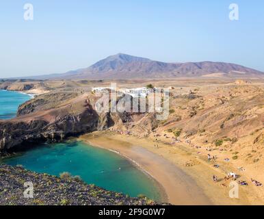 Playa Blanca, Lanzarote, Kanarische Inseln, Spanien. Blick über Playa del Papagayo von der Klippe über dem Strand, Atalaya de Femés im Hintergrund. Stockfoto