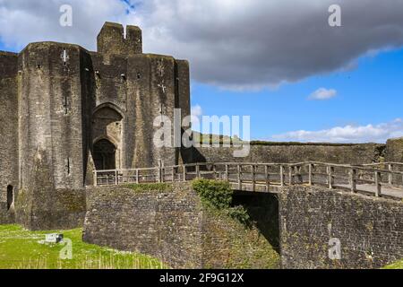 Caerphilly, Wales - April 2021: Brücke über den Graben und Türme am Eingang zum Schloss Caerphilly in Südwales. Stockfoto