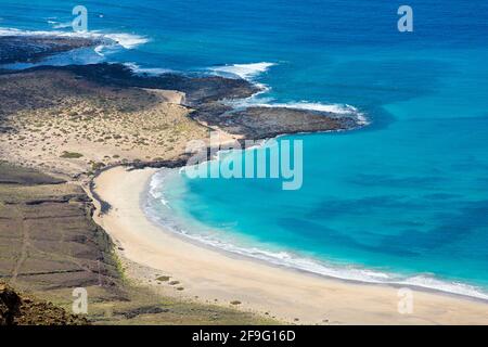 Haría, Lanzarote, Kanarische Inseln, Spanien. Blick über das türkisfarbene Wasser vor Playa del Rojo vom Mirador del Río. Stockfoto