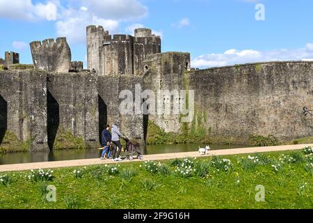 Caerphilly, Wales - April 2021: Menschen, die auf dem Fußweg um Caerphilly Castle in Südwales wandern. Stockfoto