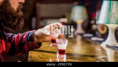 Trinken von Alkohol in Schnapsgläser in einem Nachtclub oder einer Bar. Bärtiger Mann Schüsse Cocktail. Tequila Shots, Wodka, Whisky, Rum. Barkeeper im Pub. Tequila-Schuss Stockfoto