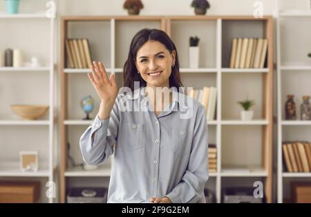 Frau winkt mit der Hand vor die Kamera, während sie ein Video aufnimmt oder einen Online-Anruf führt. Stockfoto