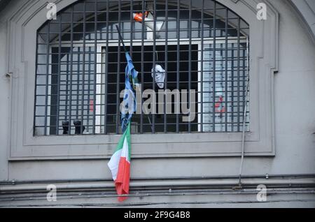 Nahaufnahme eines Fensters mit einem Metallzaun Und die zerrissene italienische Flagge, die an der Stange befestigt war, ragte heraus Stockfoto