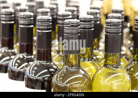 Weinflaschen in einer Reihe, selektiver Fokus. Spirituosengeschäft, Weiß- und Rotwein-Produktionskonzept Stockfoto