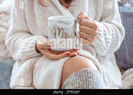 Eine Frau, die einen Strickpullover trägt und einen großen hält tasse mit dem aufgedruckten Wort Mrs Stockfoto