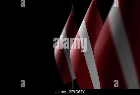 Kleine Nationalflaggen Lettlands auf schwarzem Hintergrund Stockfoto