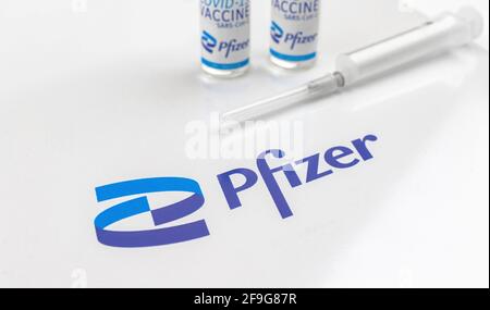 Charkow, Ukraine - 18. April 2021: Nahaufnahme mit Pfizer-Logo und Impfstofffläschchen auf weißem Glastisch in einem Krankenhaus Stockfoto