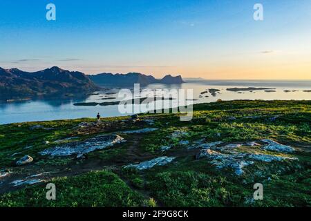 Luftaufnahme eines Mannes und eines Zeltes auf einem Berg, in Senja, Norwegen, Mitternachtssonne - Rückdrohnenschuss Stockfoto