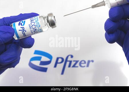 Charkow, Ukraine - 18. April 2021: Arzt impfen mit Pfizer COVID-19-Impffläschchen, Nahaufnahme mit Logo Stockfoto