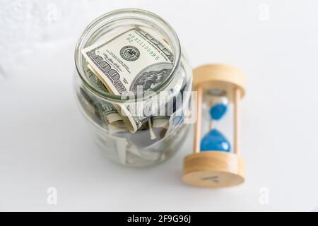 Faltet Geld in einem Glas auf einem weißen Holzhintergrund. Der Ort des Hintergrundbildes für Text. Stockfoto