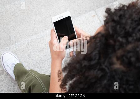 Frau, die ein Mobiltelefon benutzt, während sie auf der Treppe sitzt. Draufsicht. Stockfoto