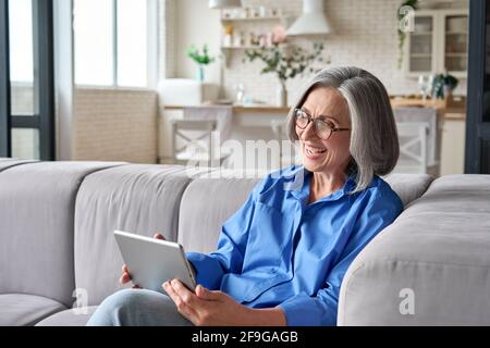 Ältere Frau zu Hause beim Video-Meeting mit Familienfreunden auf dem Tablet. Stockfoto