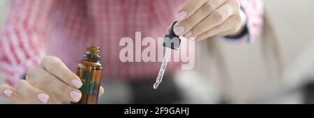 Weibliche Hände tropfende Marihuanaöl Tropfen von der Pipette in den Becher Nahaufnahme Stockfoto