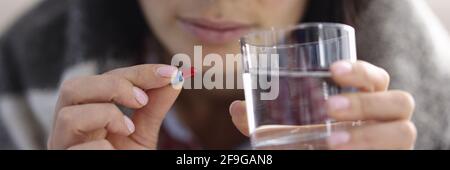 Kranke Frau hält Glas Wasser und Kapsel mit Medizin In den Händen Nahaufnahme Stockfoto