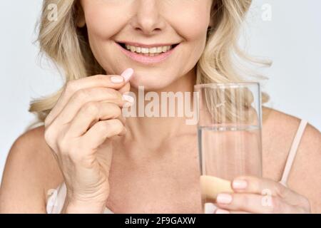 Beschnittenes Nahaufnahme-Porträt einer älteren Frau, die Schönheitskollagen-Pillen nimmt. Stockfoto